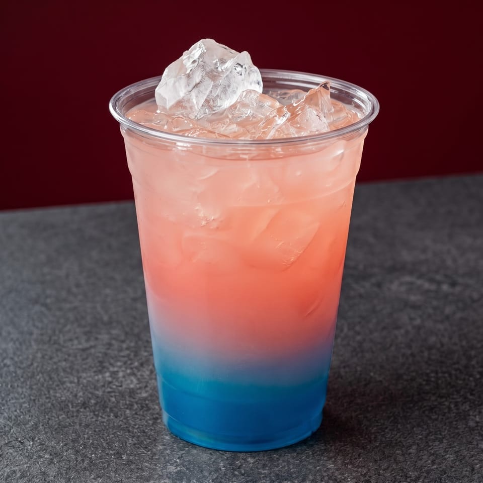 A vibrant, layered drink with blue on the bottom, pink in the middle, and ice on top.